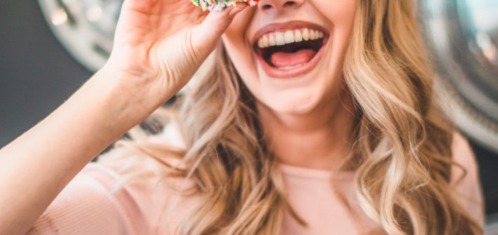Laughing woman holding a donut | self care ideas