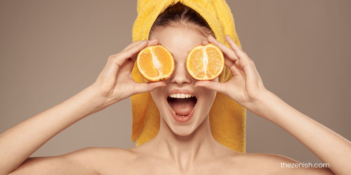 woman covering each of her eye with half an orange 